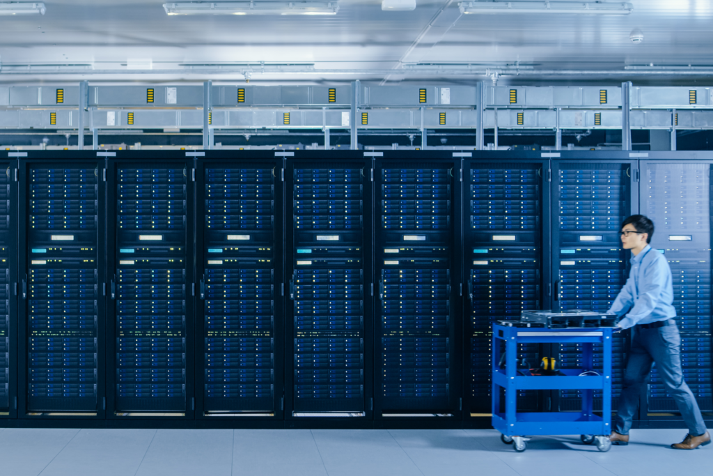 Rows of server racks in a data center with a technician working.